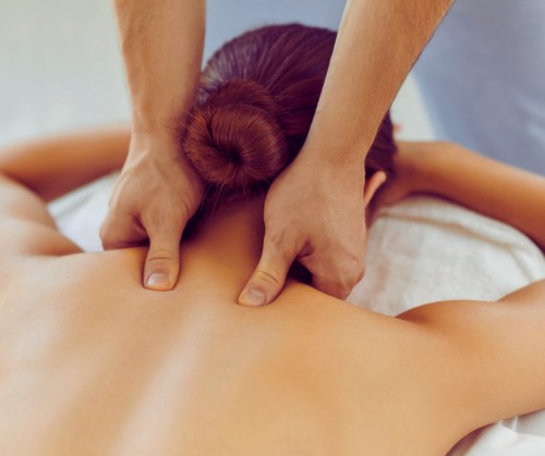 A person receiving a back massage, with hands applying pressure to the upper back.