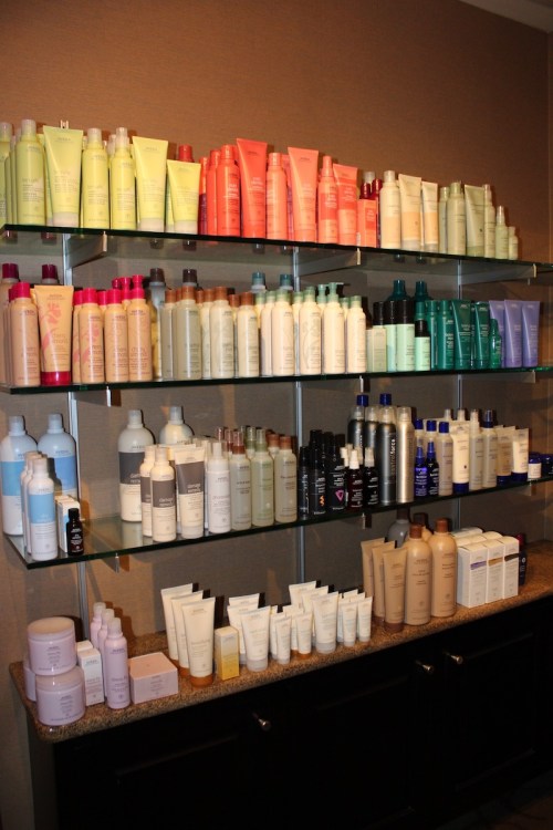 A neatly organized shelf displaying a variety of colorful hair and skincare products in bottles and tubes.