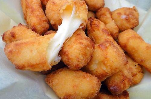 A close-up of golden-brown, crispy cheese curds, some with melted cheese stretching between them.