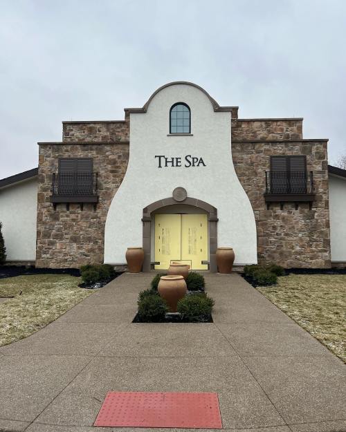A stone and stucco building labeled "The Spa," featuring a curved roof and a pathway lined with planters.