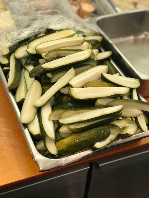 A tray filled with cut cucumber halves, arranged neatly and ready for preparation.