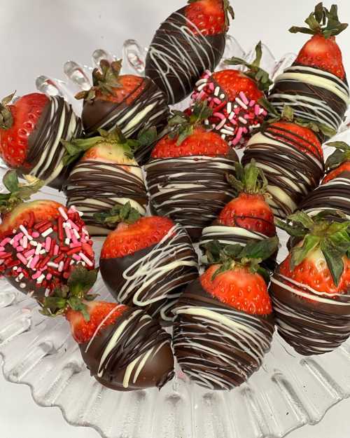 A platter of chocolate-covered strawberries, decorated with white chocolate drizzle and colorful sprinkles.