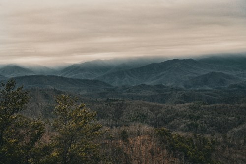 A misty mountain landscape with layered peaks and a cloudy sky, showcasing a serene, natural environment.