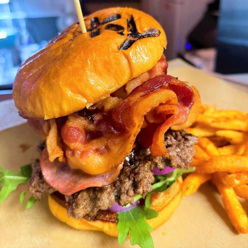 A juicy burger with bacon, lettuce, and onion, served with crispy fries on the side.