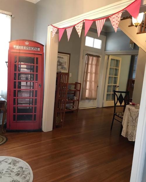 A cozy hallway featuring a red phone booth, wooden furniture, and decorative bunting.