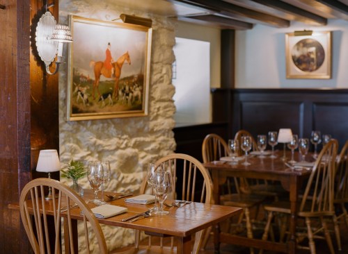 Cozy restaurant interior with wooden tables, elegant table settings, and horse-themed artwork on the walls.