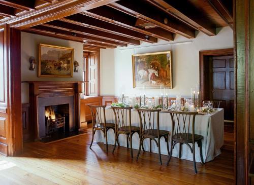 A cozy dining room with a wooden table set for a meal, featuring a fireplace and artwork on the walls.
