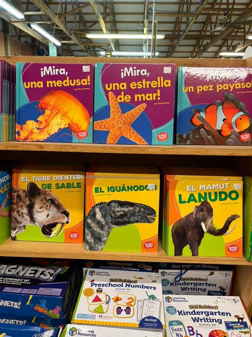 Colorful children's books on a shelf, featuring animals like a jellyfish, starfish, clownfish, tiger, iguana, and mammoth.