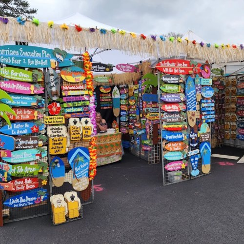 Colorful market stall with signs and decorations, featuring a variety of playful and humorous beach-themed items.