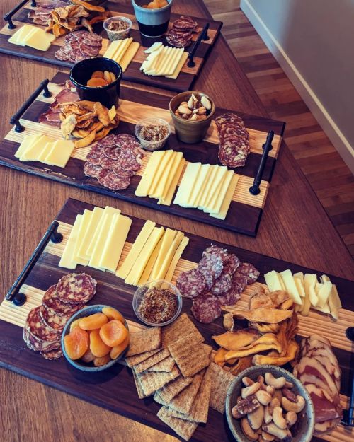 A beautifully arranged charcuterie board with various cheeses, meats, nuts, and dried fruits on wooden platters.
