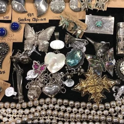 A collection of vintage jewelry pieces, including brooches, earrings, and necklaces, displayed on a black background.