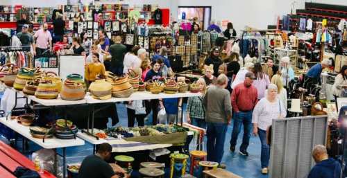 A bustling market scene with people browsing various handmade crafts and colorful baskets on display.