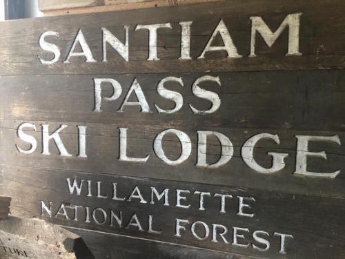 Wooden sign for Santiam Pass Ski Lodge in Willamette National Forest, featuring bold white lettering.