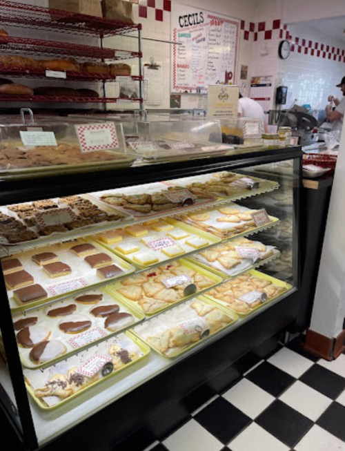 Display case filled with various baked goods, including pastries and cookies, in a bakery with a checkered floor.