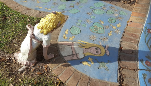 A colorful mural on a pathway featuring a girl with blonde hair and a rabbit, surrounded by painted leaves and flowers.