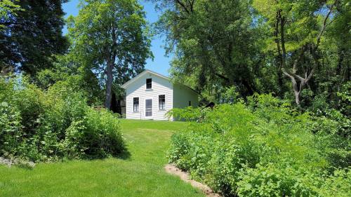 A white house surrounded by lush greenery and trees under a clear blue sky.