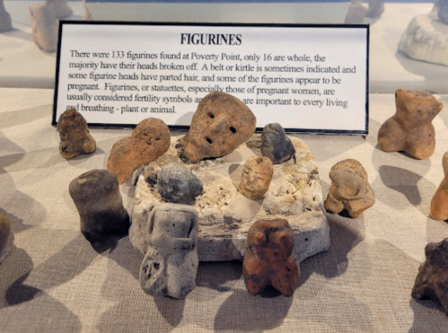 Display of ancient figurines from Poverty Point, with a sign explaining their significance and condition.
