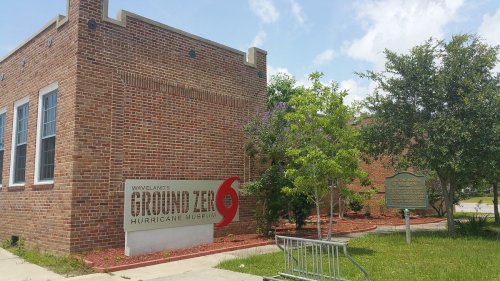 Exterior of the Ground Zero Hurricane Museum, featuring a brick building and signage, surrounded by greenery.