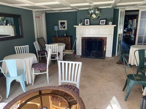 Cozy room with tables and chairs, a fireplace, and decorative wall art, creating a welcoming atmosphere.