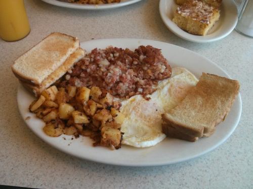 A plate of breakfast featuring eggs, hash browns, toast, and diced potatoes.