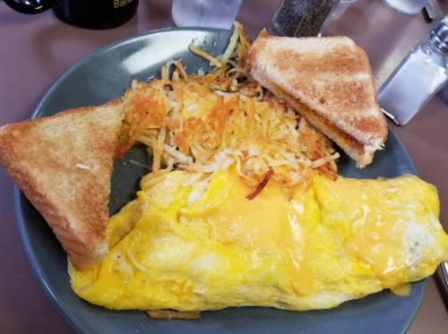 A plate with a cheese omelet, crispy hash browns, and two slices of toasted bread.