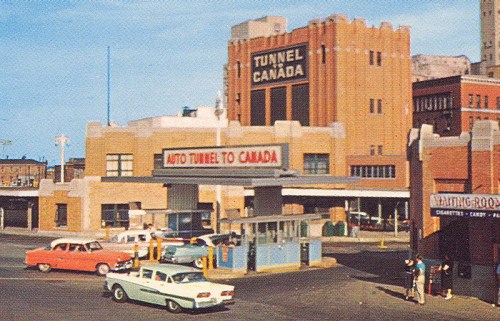 Historic image of an auto tunnel entrance to Canada, featuring vintage cars and a distinctive building.