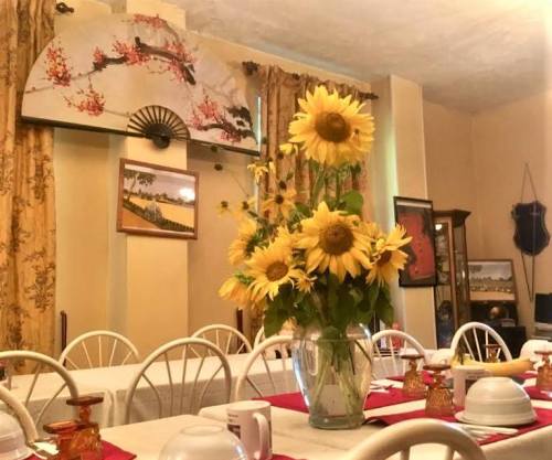 A dining room with a table set for a meal, featuring a vase of sunflowers and decorative wall art.