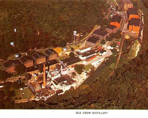 Aerial view of Old Crow Distillery, surrounded by trees and buildings, showcasing industrial structures and a water tower.