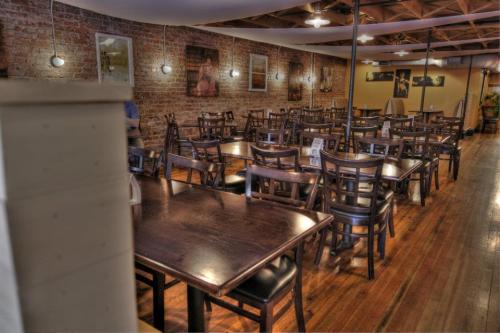 Cozy restaurant interior with wooden tables and chairs, exposed brick walls, and warm lighting.