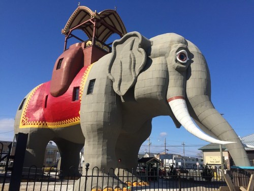 A large, colorful elephant-shaped structure with a tower on its back, set against a clear blue sky.