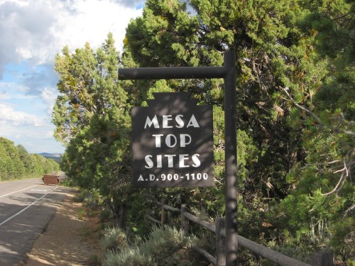 Sign for Mesa Top Sites, indicating historical significance from A.D. 900-1100, surrounded by trees and a road.