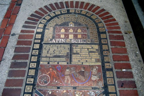 A decorative brick plaque featuring historical information about Boston Latin School and its founding.