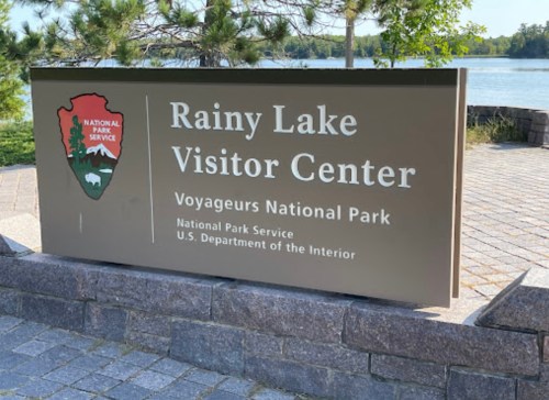 Sign for Rainy Lake Visitor Center at Voyageurs National Park, featuring the National Park Service logo.