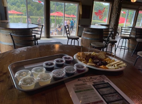 A wooden table with a tray of dipping sauces and a platter of snacks, overlooking a scenic outdoor area with umbrellas.