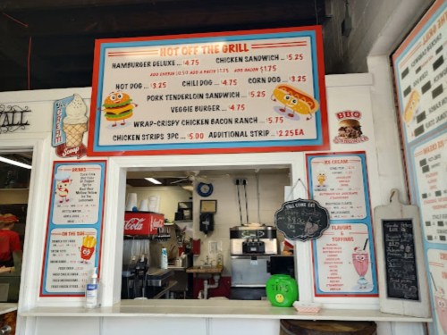 Menu board featuring various food items and prices, including burgers, hot dogs, and chicken strips.