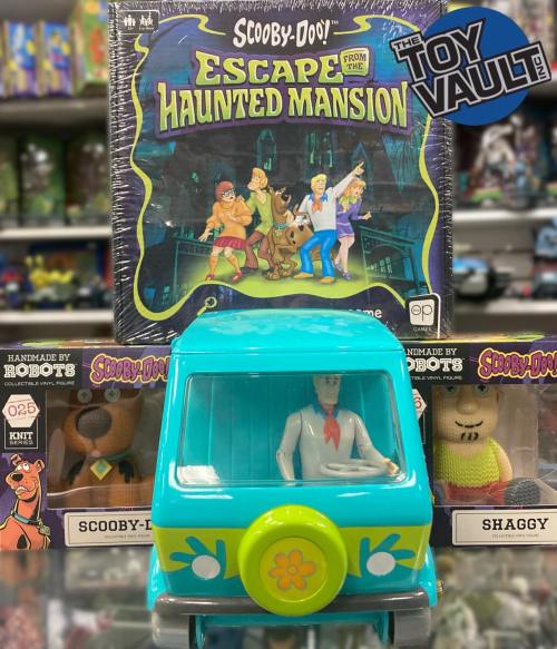 A Scooby-Doo toy van in front of a "Escape from the Haunted Mansion" game and collectible figures of Scooby and Shaggy.