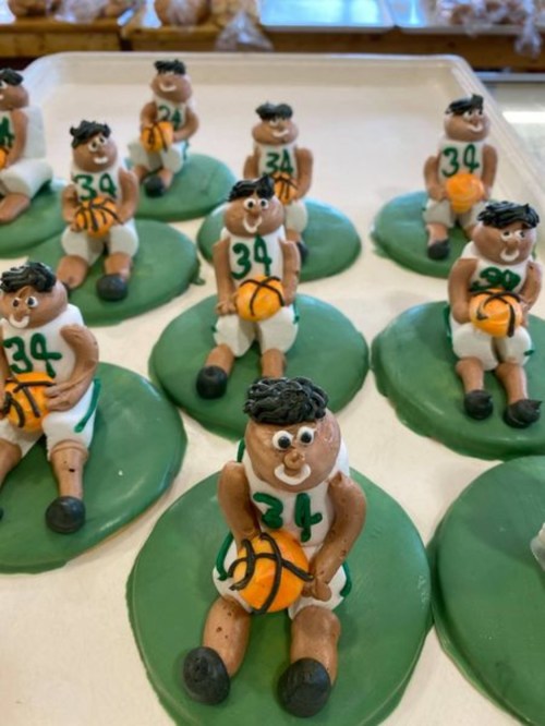 A tray of cookie figures shaped like basketball players, each holding a ball and sitting on green bases.
