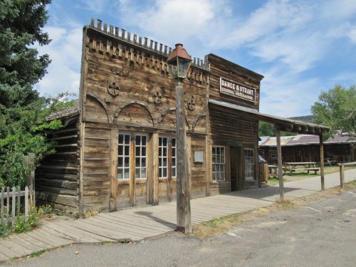 A rustic wooden building with a sign reading "Dance & Stuart" in a historic western-style setting.