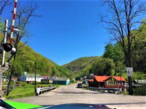 A scenic view of a small town with colorful houses, surrounded by green hills under a clear blue sky.