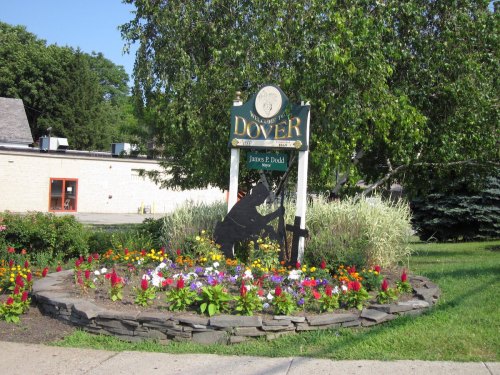 Sign for Dover, featuring a silhouette of a soldier and a flower bed with colorful blooms.