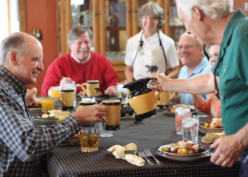 A group of people enjoying a meal together at a table, smiling and sharing drinks and food.