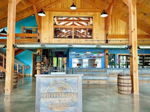 Interior of a rustic barn with wooden beams, a bar area, and colorful decor, featuring a spacious and inviting atmosphere.