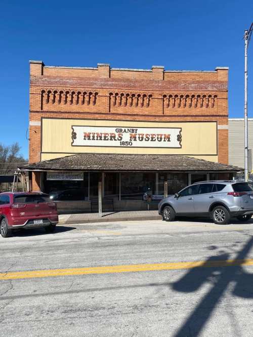 Exterior of the Granby Miners Museum, a brick building with a sign, set against a clear blue sky.