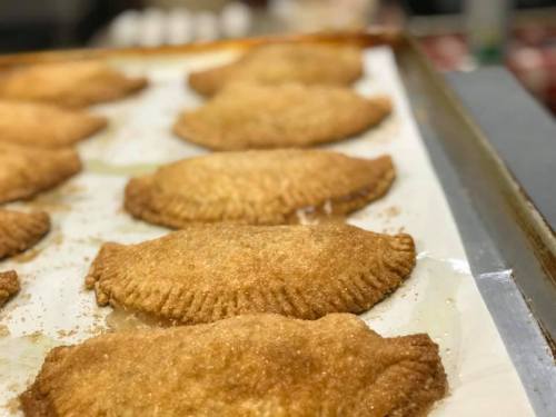 Golden-brown baked pastries arranged on a tray, with a crispy texture and a light dusting of sugar.