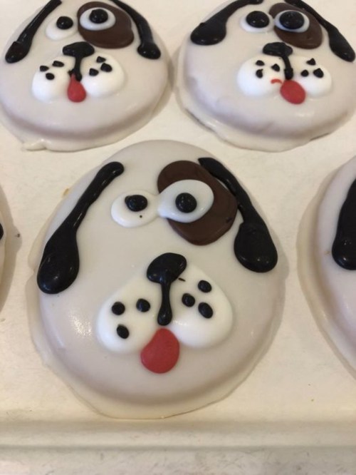 Cute dog-shaped cookies decorated with icing, featuring big eyes, floppy ears, and playful expressions.