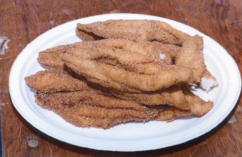 A plate of golden-brown fried fish fillets arranged neatly on a white paper plate.