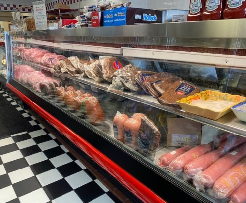 A display case filled with various meats, including sausages, steaks, and packaged products, in a butcher shop.