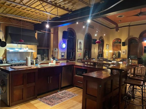 A spacious kitchen with wooden cabinets, a large island, and modern appliances, illuminated by warm lighting.