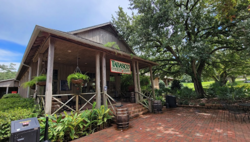 A rustic building with a sign reading "Tabasco" surrounded by greenery and brick pathways.