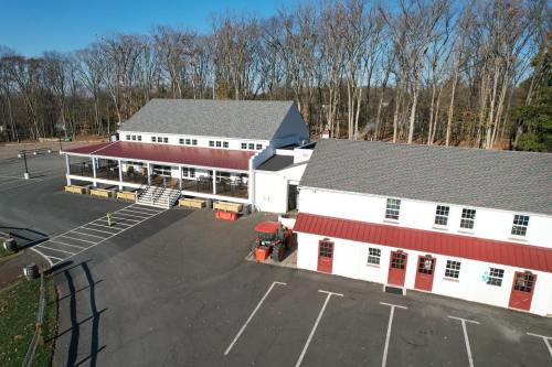 Aerial view of a large building with a gray roof, surrounded by trees and an empty parking lot.